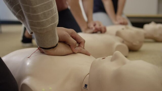 First aid certification training class practicing chest compression on dummy