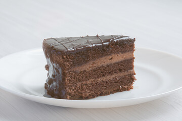 Chocolate cakeclose-up is on a white plate. Light background. Nature light - 481055768