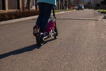 A woman rides an electric scooter in a cottage village with a dog Jack Russell Terrier. 