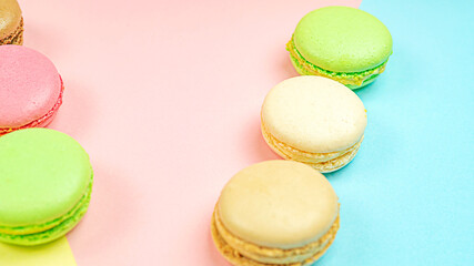 Multicolored macaroon cakes on colored bedding background with copy space