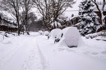  As a blizzard sweeps into a residential neighbourhood the streets fill with snow and residents start to shovel out their cars and sidewalks. Shot in the Toronto’s Beaches  in January. Room for text.