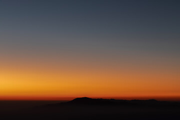 Heaven at early morning with copy space. Sunset, sunrise backdrop.Predawn clear sky with orange horizon and blue atmosphere. Smooth orange blue gradient of dawn sky.