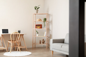 Interior of light room with modern workplace and shelving unit