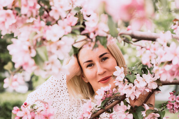 Young woman among the blossoming trees. Spring nature park or garden, flowering trees. Concept spring woman health