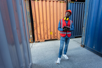 Male African American person foreman using tablet checking list containers loading. Industrial logistics import export and shipping.