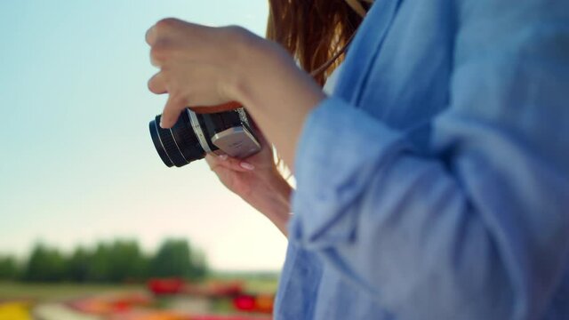 Closeup woman hands holding professional photo camera in blooming garden outdoor