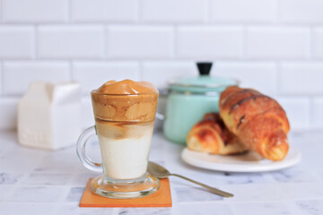 dalgona coffee in transparent cup and fresh croissant