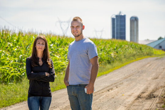 Proud couple of farming entrepreneurs looking at the camera in a corn field. High quality photo