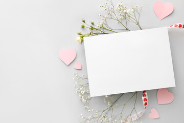 Composition with blank card, flowers and paper hearts on white background. Valentine's Day celebration