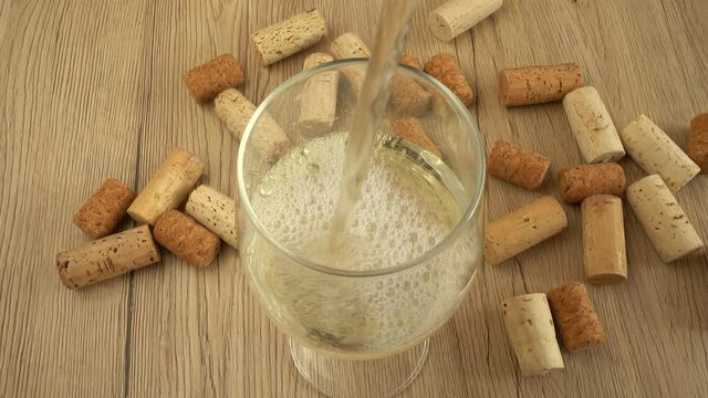 Wine is poured into a glass on the background of wine corks.