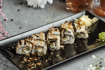 Golden dragon sushi roll with tuna, eel, cucumber, sesame seeds and tobiko caviar on wood background