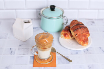 dalgona coffee in transparent cup with croissant - topview