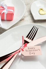 Beautiful table setting and tag with text HAPPY VALENTINE'S DAY on table, closeup