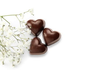 Obraz na płótnie Canvas Tasty heart-shaped candies and flowers on white background