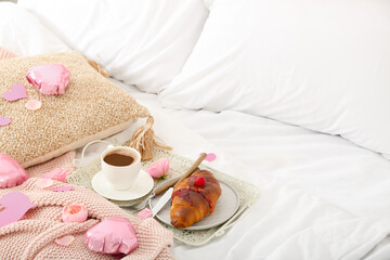 Tray with delicious breakfast and hearts on soft bed