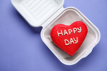 Plastic lunch box with tasty bento cake for Valentine's Day on purple background