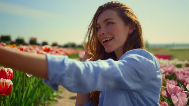 Young woman making selfie in beautiful flower garden. Girl smiling in smartphone