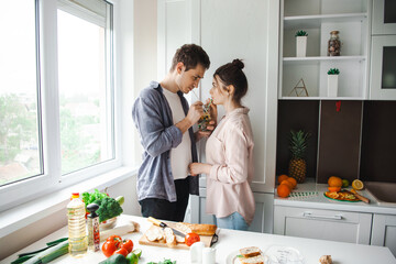 Caucasian couple drinking smoothie with a straw in the kitchen. Healthy meal.