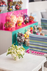 Centerpiece with flowers in the foreground. In the background shelves with sweets, candy bar Style. festive setting