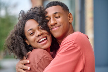 Close-up dark-skinned man and woman hugging outdoors