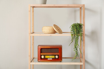 Wooden bookcase with retro radio receiver near light wall
