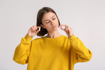 Young woman with chewing gum on light background