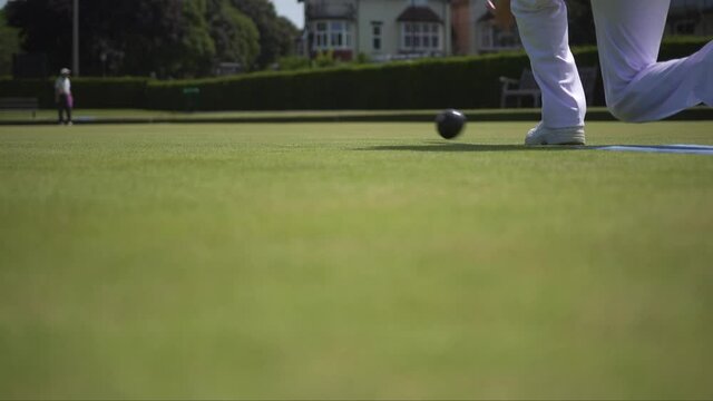 A bowls player playing his shot down the green.