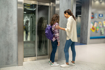 Joyful woman and a kid waiting for the passenger lift