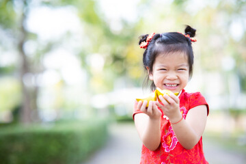 Portrait laughing kid girl was holding two gold coins. Chinese New Year greeting concept. Child wear red cheongsam. Empty space to enter text.