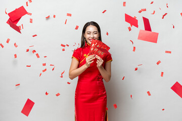 Smiling happy Asian woman in traditional oriental costume holding red envelopes Ang Pow in gray...