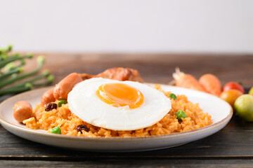 Fried rice with chicken, sausage and fried egg on wooden table