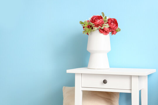 White table with flowers in vase on blue wall background