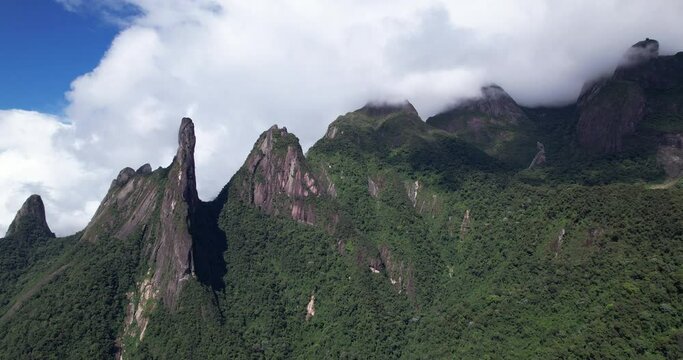 Aerial sideways movement panning around panorama landscape of Brazil mountain range Serra dos Orgaos of Teresopolis in Rio de Janeiro with the Finger of God peak rock formation and cloud coverage