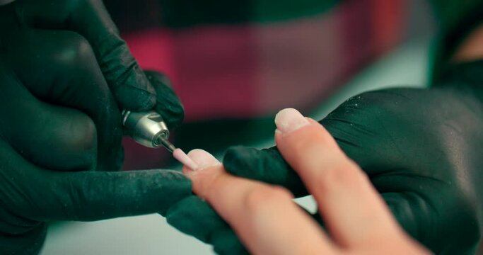 A manicurist grinds nails with a manicure machine.