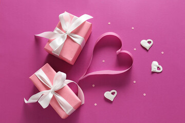 Presents for Valentine day and heart made of ribbon on color background