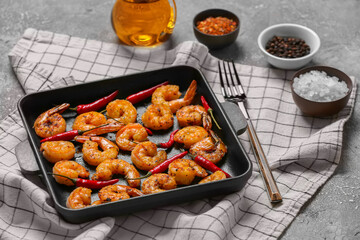 Baking dish of tasty shrimp tails on grey background