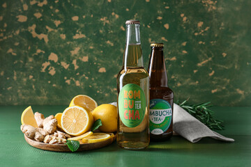 Bottles of fresh kombucha with ingredients on table