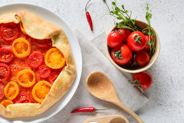 Plate with tasty tomato galette on light background
