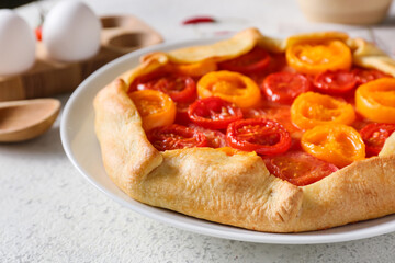 Plate with tasty tomato galette on light background, closeup