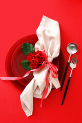 Beautiful table setting for Valentine's Day and rose flower on red background