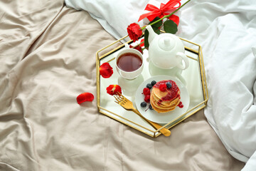 Tray with tasty breakfast and rose flower for Valentine's Day on bed