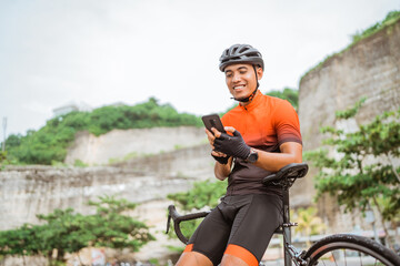 road bike cyclist sitting on his bike while using mobile phone