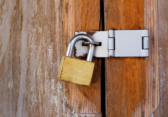 Vintage locked padlock with chain at brown wooden door background