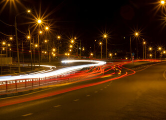 Moving car with blur light through roads and highways in twilight city. Night cityscape.