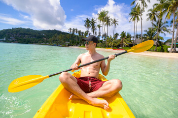 A young sporty man kayaking at the ocean in a sunny day