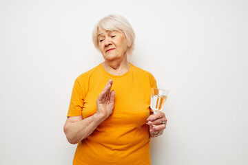 Cheerful elderly woman holding a glass of water health light background