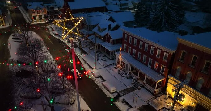 Christmas star over town square covered in winter snow at night. Pretty beautiful scene in America. Aerial turn.