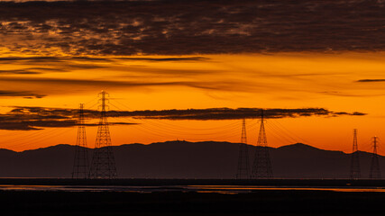 Fototapeta premium Electrical power lines seen at sunset in the wetlands
