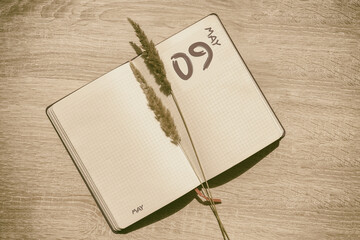 may 9. 9th day of month, calendar date.Blank pages of notebook are beige, with dried spikelets. Concept of day of year, time planner, spring month.