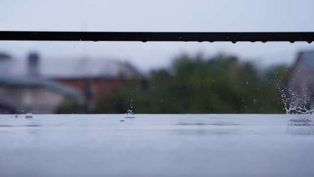 Drops of rain falling onto the balcony. Rainy afternoon in the countryside. Slow motion. 